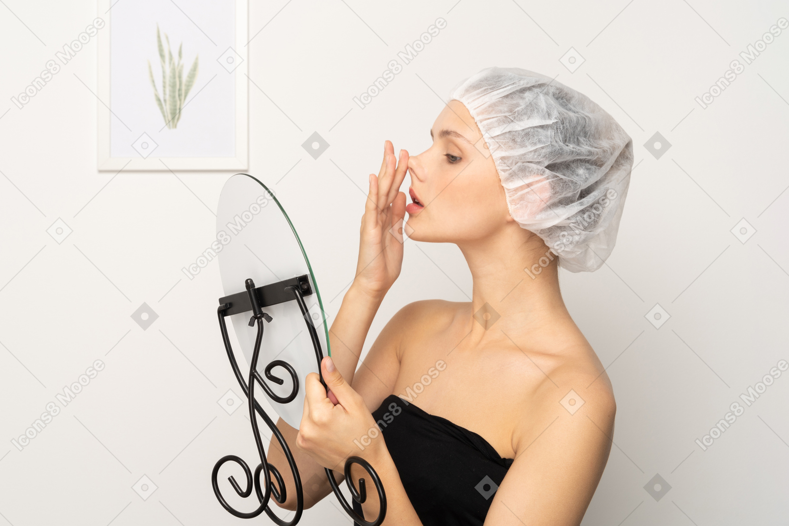 거울을 보면서 코를 들어올리는 의료 모자를 쓴 젊은 여성
