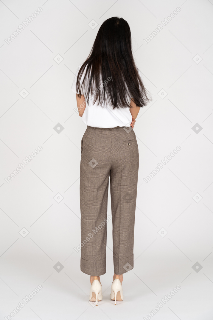 Back view of a young lady in breeches and t-shirt touching stomach