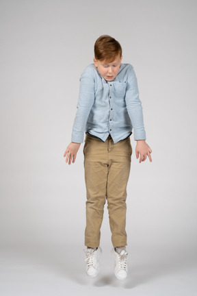 A boy in a blue shirt jumping and looking down