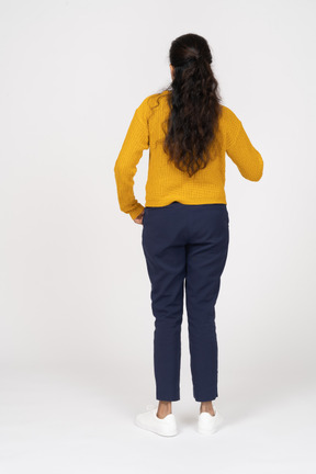 Vista posteriore di una ragazza in abiti casual in piedi con la mano in tasca