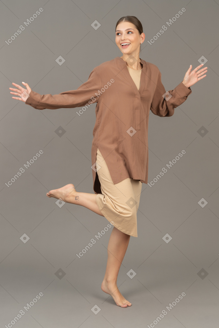 Vue de face d'une femme debout pieds nus sur la pointe des pieds avec la jambe levée