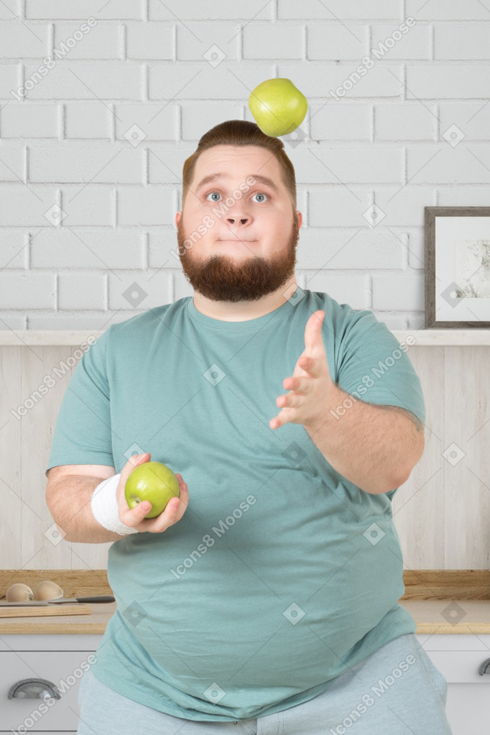 A man juggling apples in a kitchen