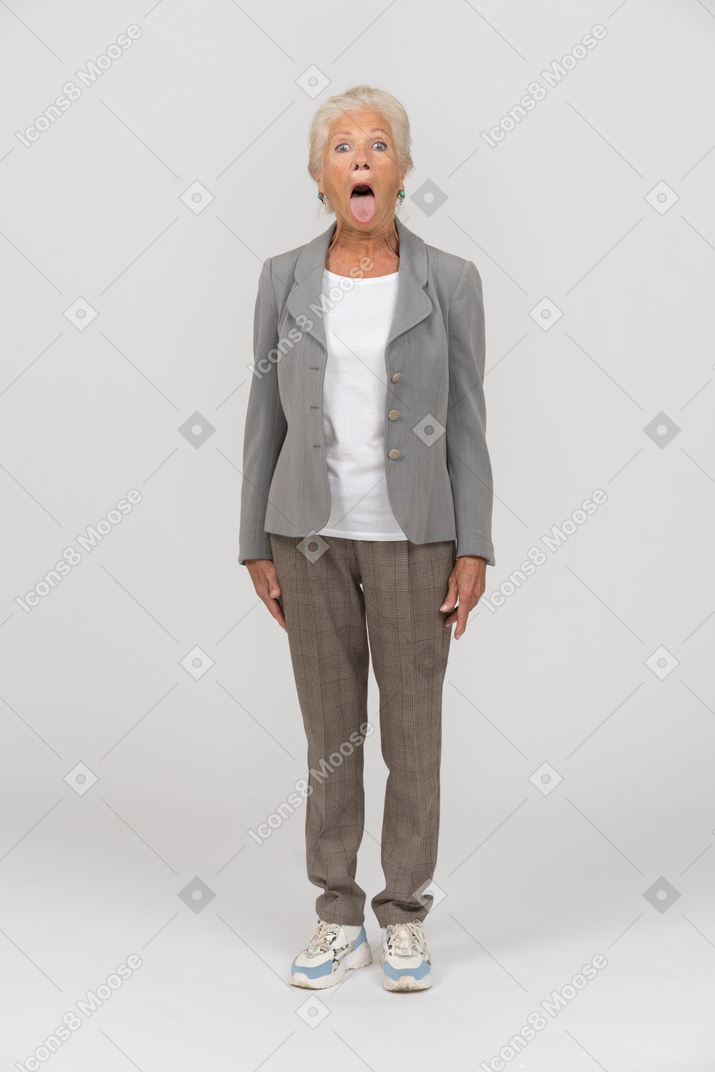 一个穿西装的老妇人的前视图，看着相机，露出舌头