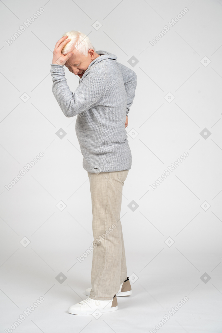 Distressed man standing and holding his hand on his head
