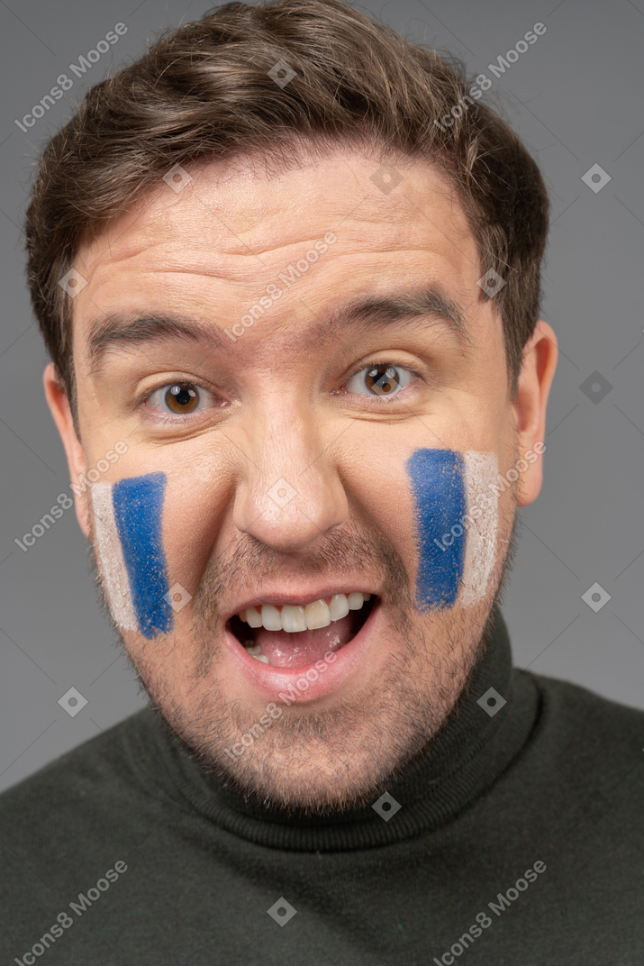 A portrait of a male football fan with blue & white face art