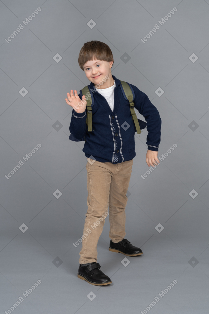 Full length portrait of a schoolboy waving