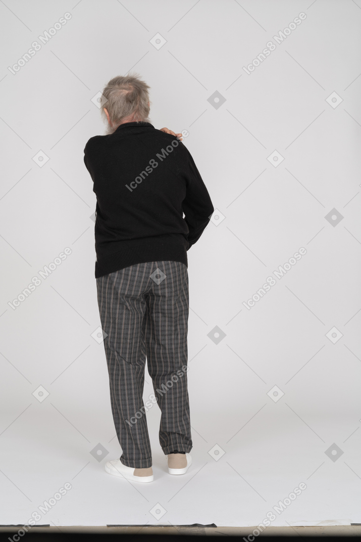 Back view of an elderly man touching his shoulder