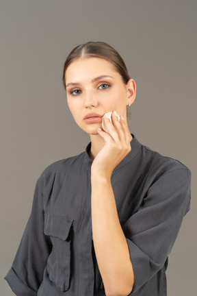 Three-quarter view of a young woman in a jumpsuit removing make-up