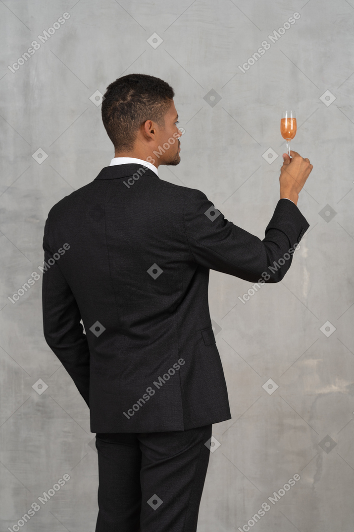 Back view of young man with flute glass proposing a toast