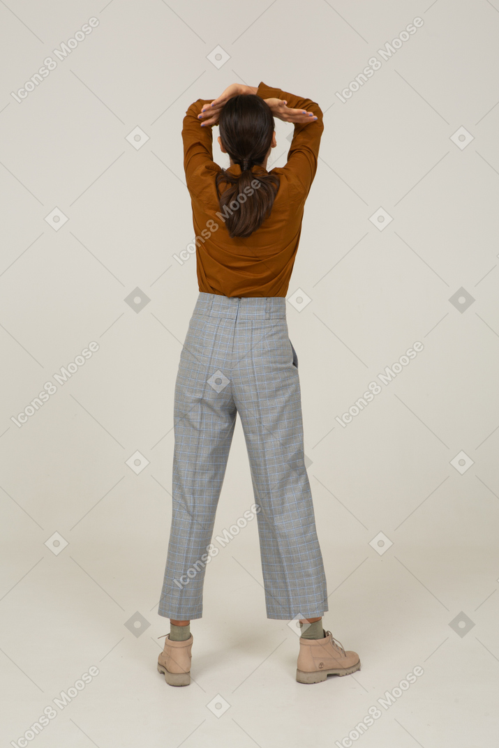 Back view of a young asian female in breeches and blouse raising hands