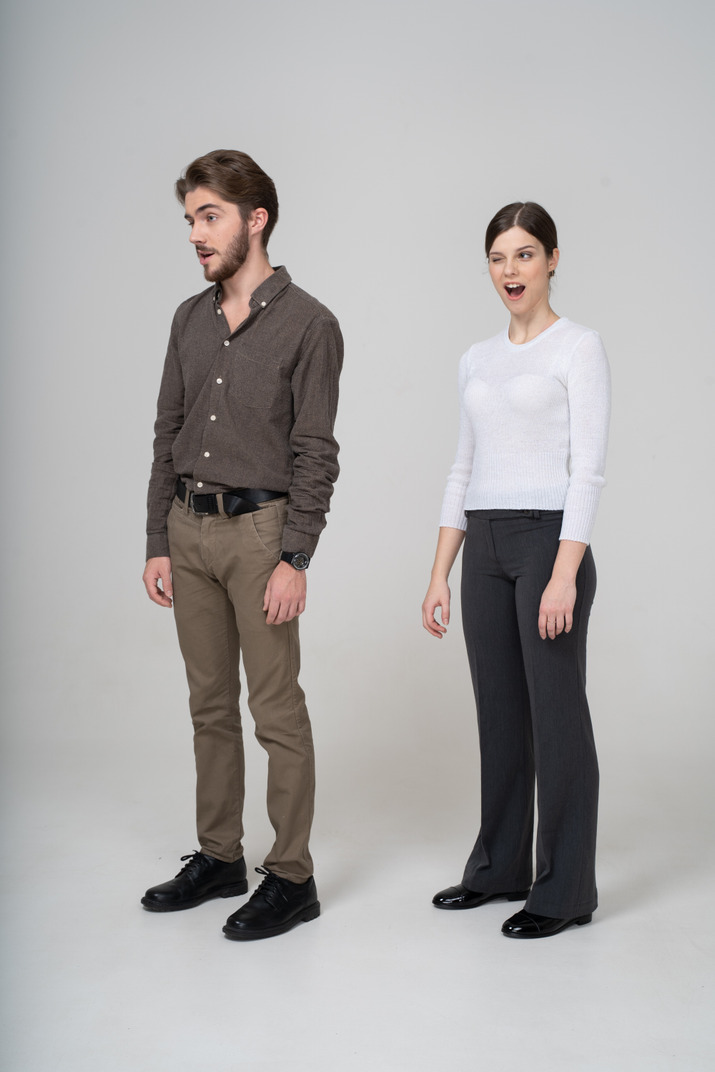 Three-quarter view of a winking young couple in office clothing