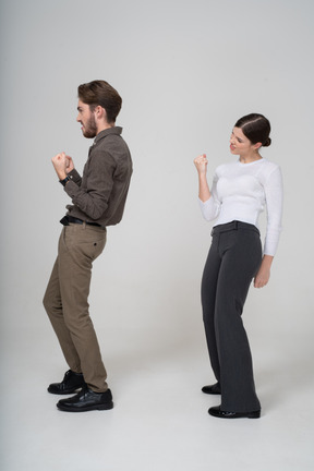 Vista lateral de um jovem casal encantado com roupas de escritório