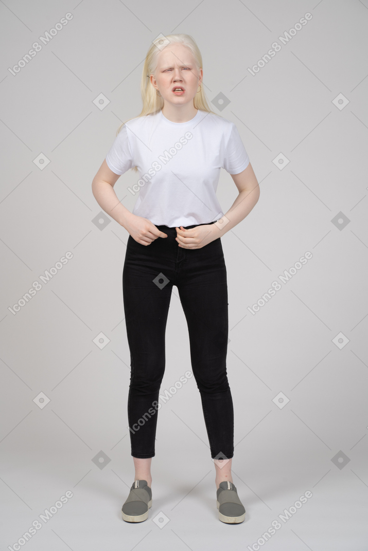 Молодая девушка держит пуговицу на джинсах