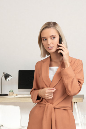 A woman in a brown suit talking on a cell phone