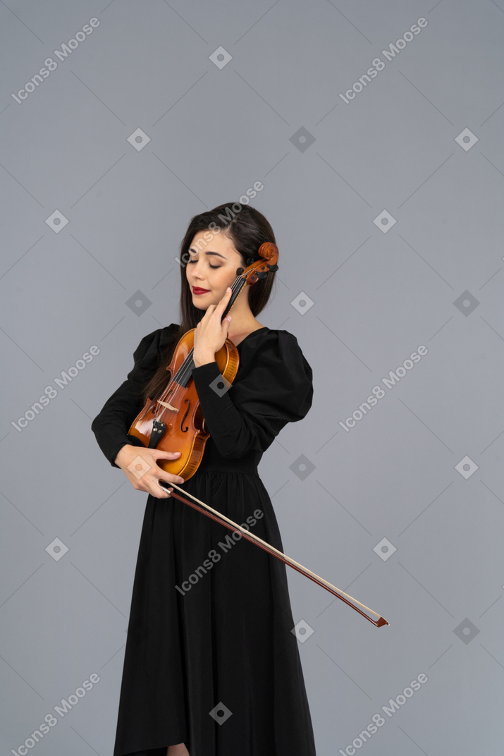 バイオリンを保持している黒いドレスを着た若い女性のクローズアップ