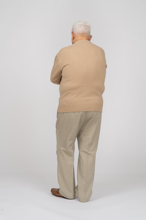 Vista trasera de un anciano con ropa informal de pie con los brazos cruzados