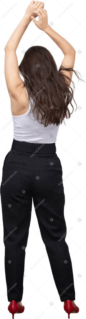 Back view of a young female in office clothing raising hands over head