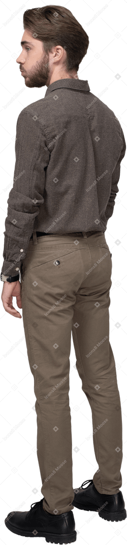 Vista posteriore di tre quarti di un giovane uomo in abiti da ufficio che soffia sulle guance