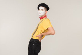 Male mime standing in profile and touching his back