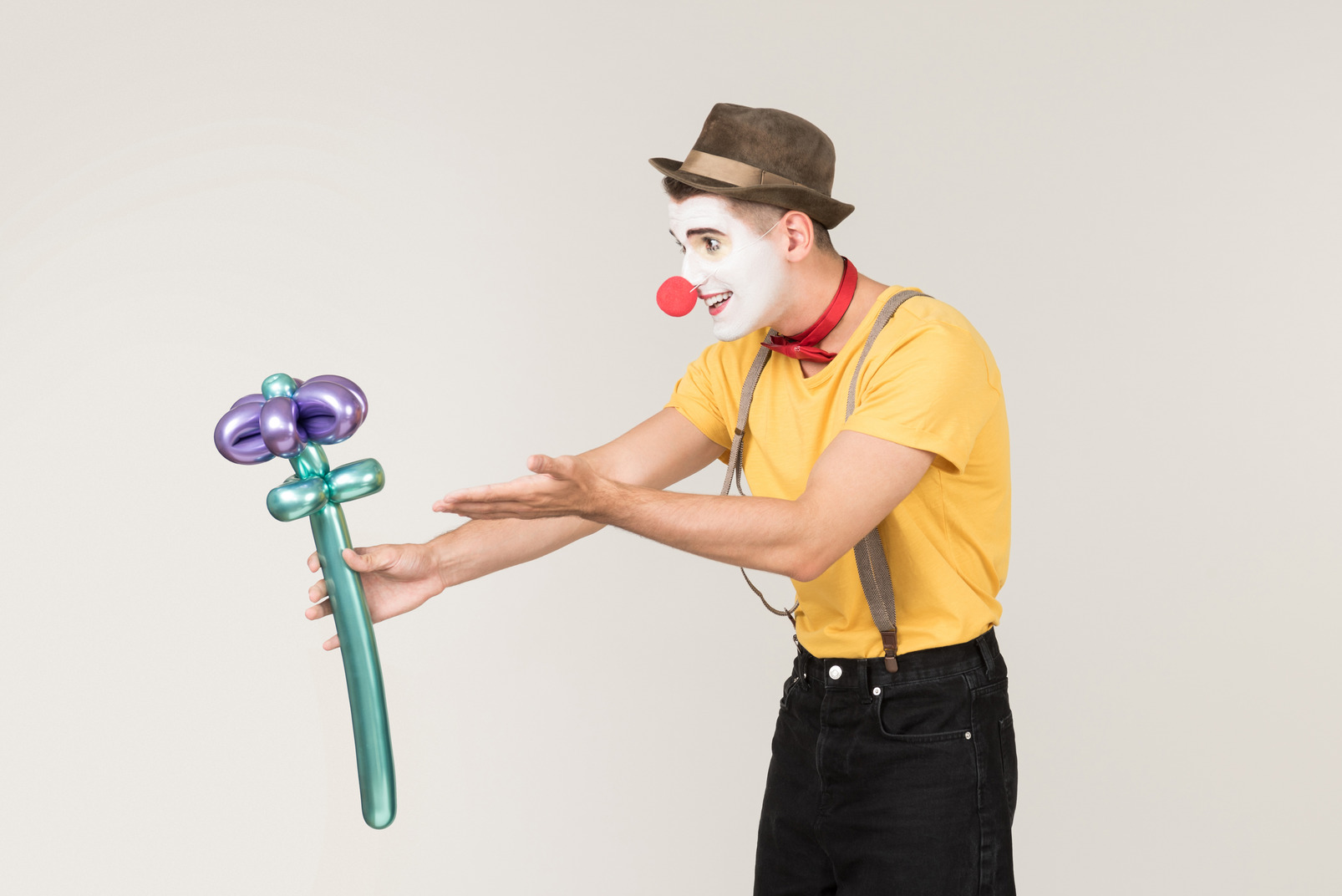 Male clown pointing at flower he's holding