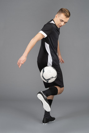 Full-length of a male football player turning away and kicking a ball