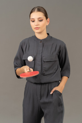 Front view of young woman in a jumpsuit playing table tennis