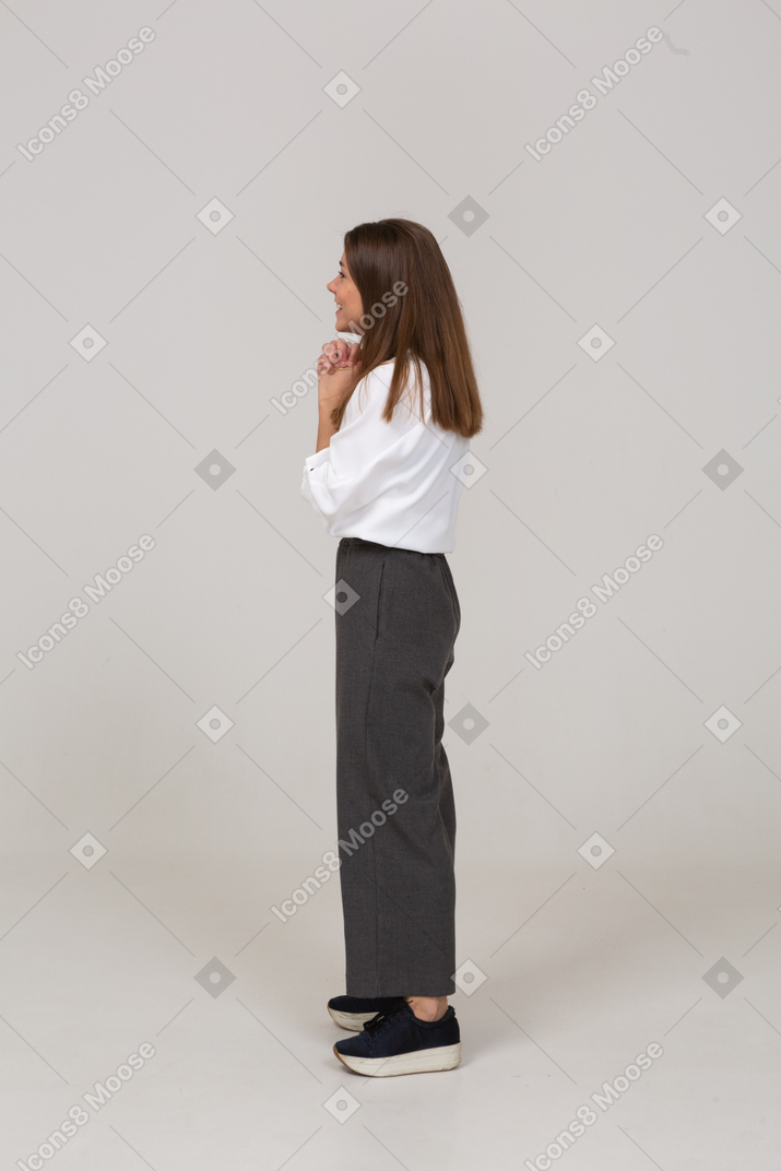 Side view of a pleased young lady in office clothing holding hands together