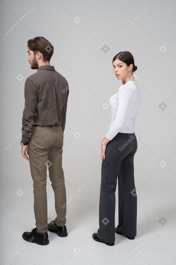 Three-quarter back view of a surprised young couple in office clothing turning away
