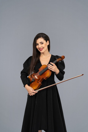 Primo piano di una giovane donna allegra in abito nero che tiene il violino