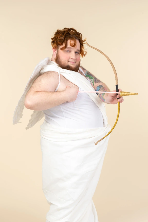 Immagini Stock - Un Ragazzino In Costume Da Cupido Con Ali E Aureola Tiene  Un Arco E Una Freccia, Mira Al Cuore, Fuoco Selettivo. Cupido Triste Spara  Al Cuore. Biglietto Di Auguri