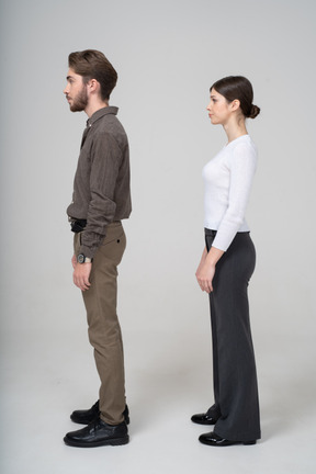 Vista lateral de um jovem casal com roupas de escritório, parado