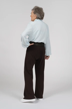 Three-quarter back view of an old woman with a hand on a hip