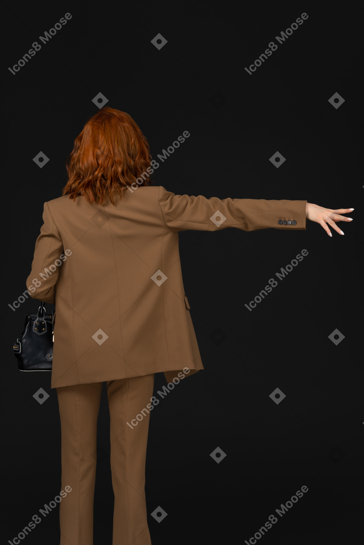 Back view of a woman in a brown suit hailing a cab