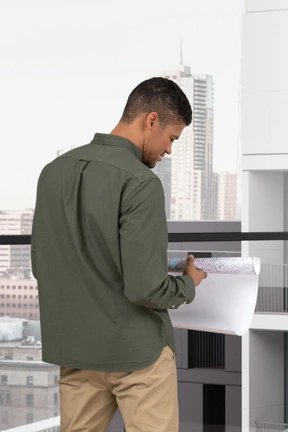 A man standing on a balcony holding a piece of paper