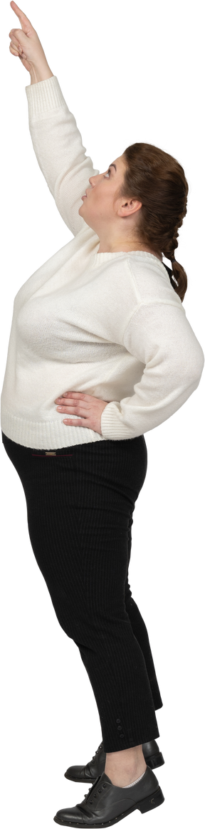 Side view of a plus size woman in casual clothes pointing up