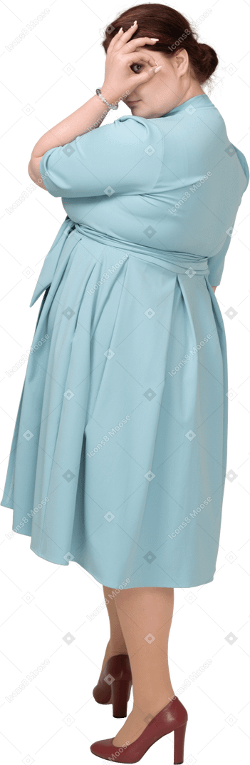 Side view of a woman in blue dress looking through fingers