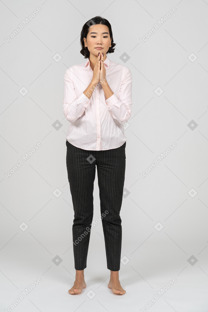 Mujer en ropa de oficina de pie con las manos cruzadas