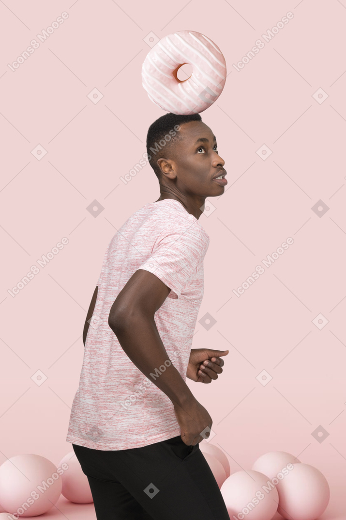 Jeune homme debout avec un gros beignet sur la tête