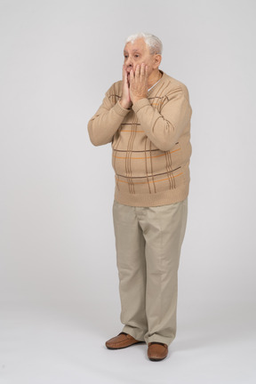 Vista frontale di un vecchio impressionato in abiti casual che coprono la bocca con le mani