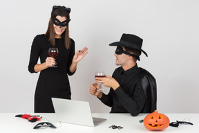Female worker in cat costume talking to male colleague dressed like a zorro