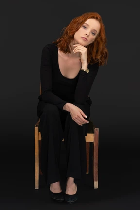 Good looking young woman sitting on the wooden chair and looking to the camera