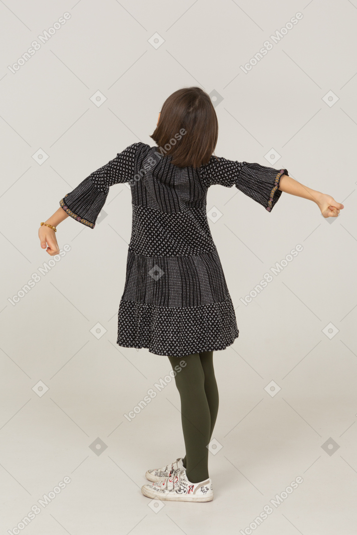 Vista posteriore di una bambina che sbadiglia in abito allargando le braccia