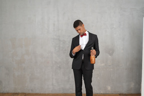 Uomo brillo in abbigliamento formale in piedi con una bottiglia di champagne