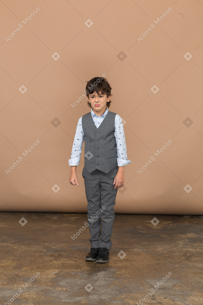 一个穿着西装的愤怒男孩站着不动的前视图