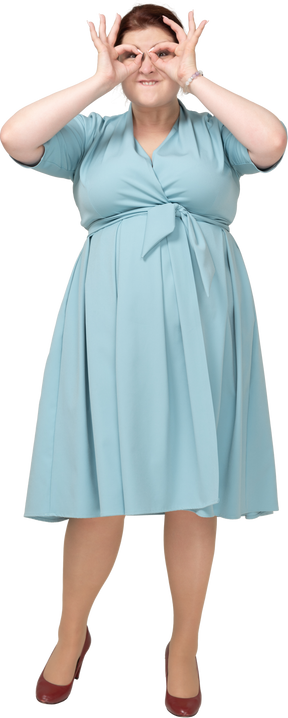 Vue de face d'une femme en robe bleue regardant à travers des jumelles imaginaires