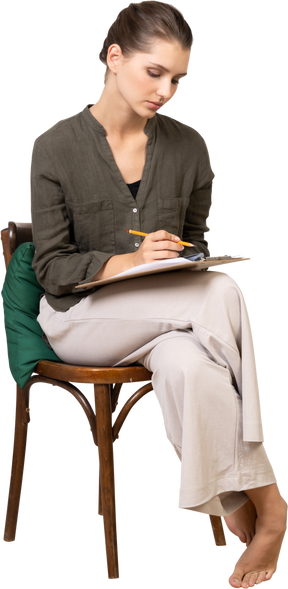 Вид спереди вдумчивой молодой женщины, сидящей на стуле во время прохождения бумажного теста
