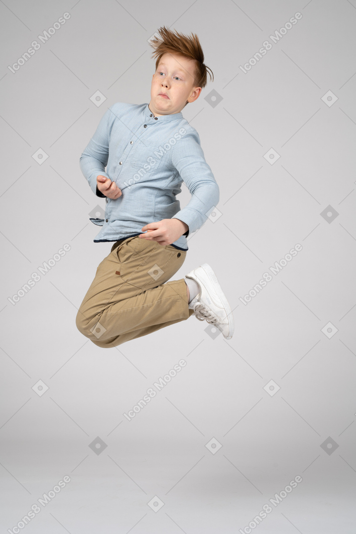 A boy in blue shirt jumping high in the air