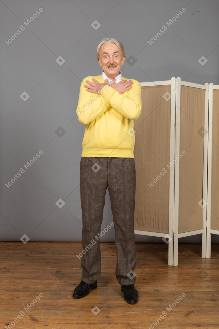 Vorderansicht eines aufgeregten alten mannes nahe dem bildschirm, der hände kreuzt