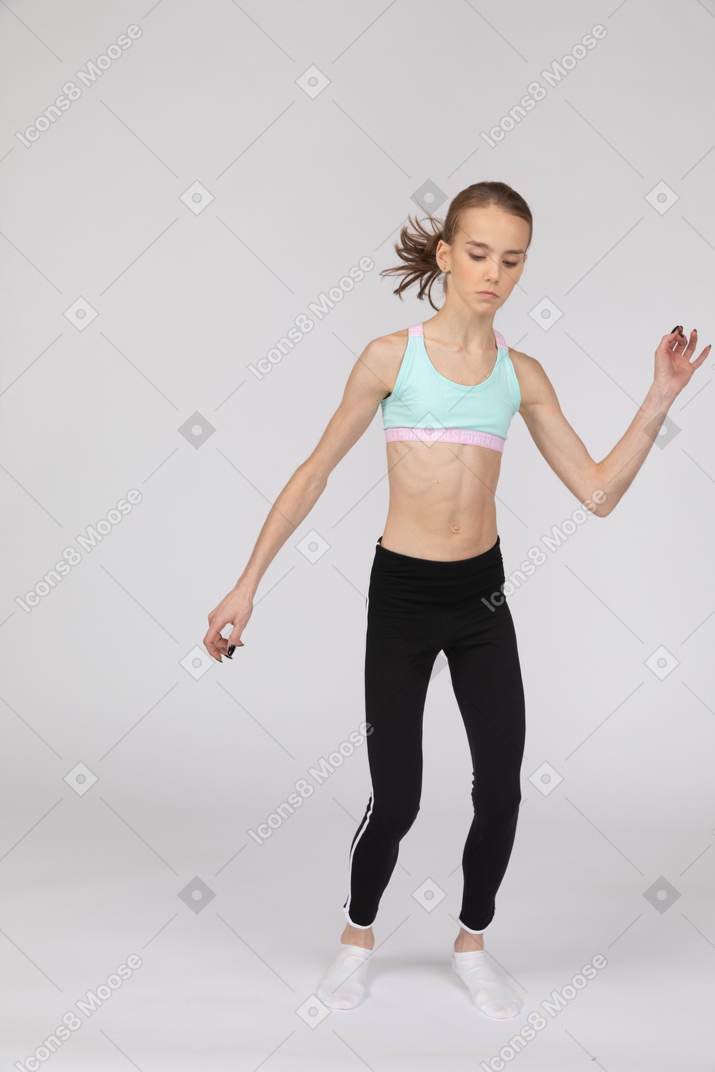 Front view of a teen girl in sportswear raising hand and looking down