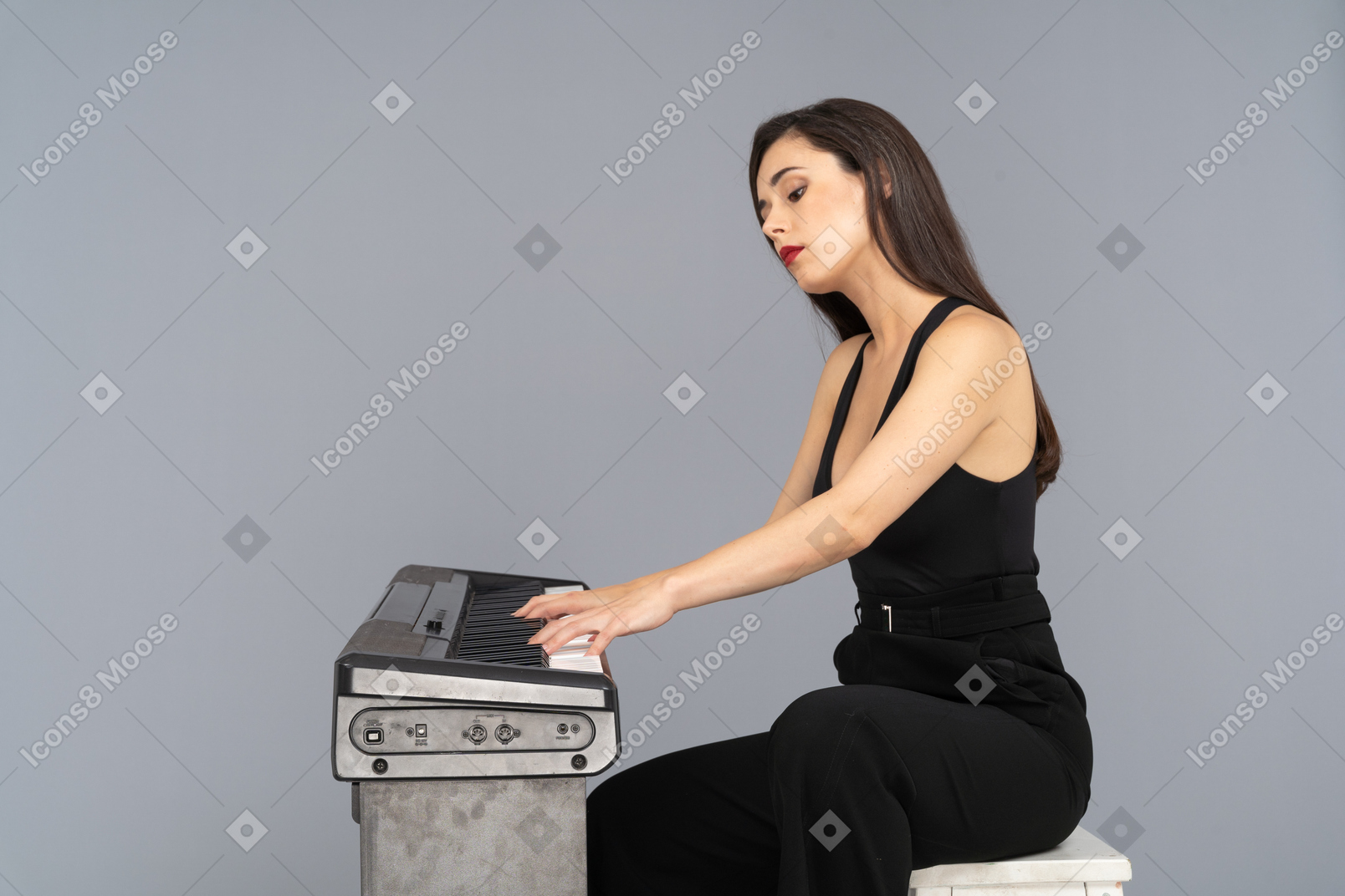 Vista lateral de uma jovem de terno preto sentada e tocando piano